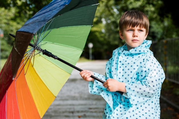 Photo gratuite petit garçon tenant un parapluie coloré