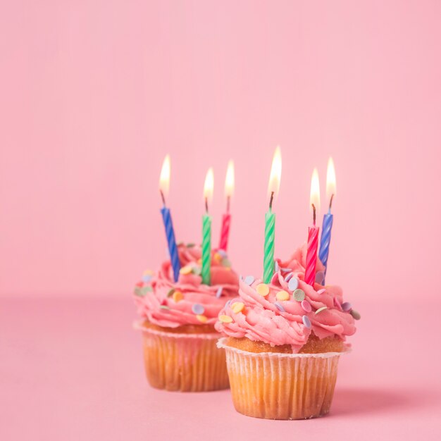 Petit gâteau d&#39;anniversaire rose allumé des bougies