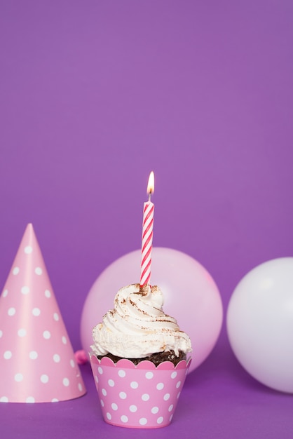 Photo gratuite petit gâteau avec une bougie allumée à côté du chapeau