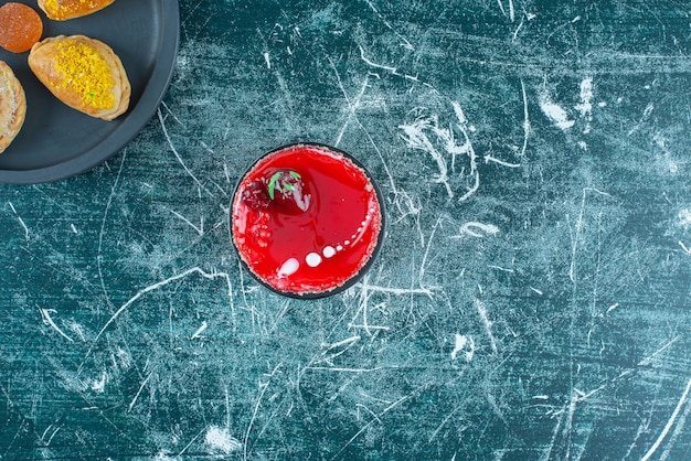 Photo gratuite petit gâteau à côté d'un paquet de petits pains sur un plat de service sur bleu.