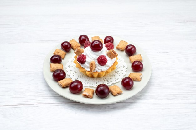 Petit gâteau crémeux aux framboises et petits biscuits sur lumière blanche