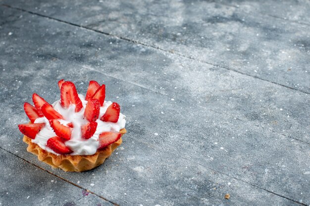 Photo gratuite petit gâteau crémeux avec des fraises en tranches sur un bureau en bois gris, couleur douce de gâteau aux baies de fruits