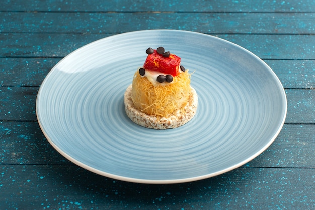 Photo gratuite petit gâteau délicieux avec de la crème et de la marmelade sur le dessus à l'intérieur de la plaque bleue sur bleu