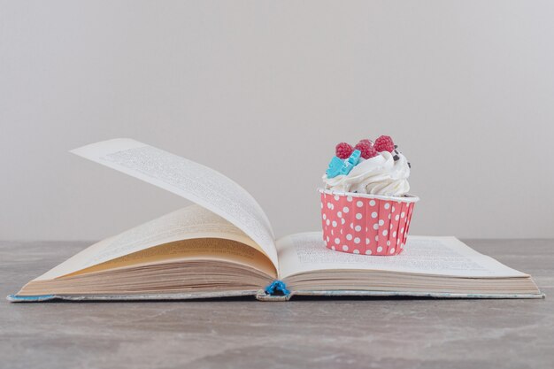 Un petit gâteau et un livre ouvert sur marbre