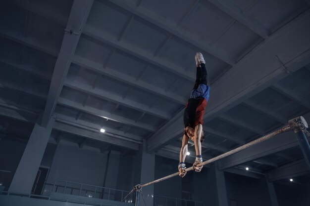 Petit gymnaste masculin s'entraînant dans une salle de sport flexible et actif