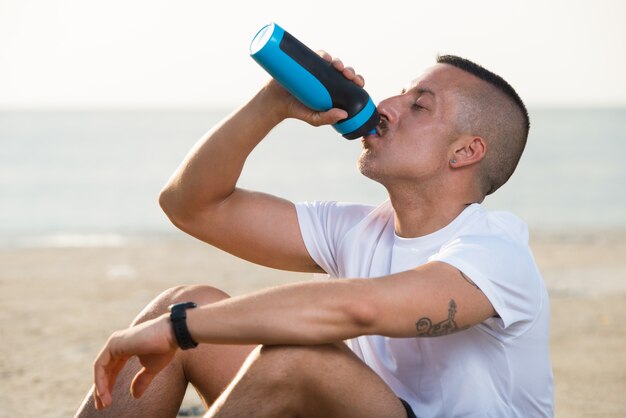 Petit homme détendu, boire de l&#39;eau de la bouteille