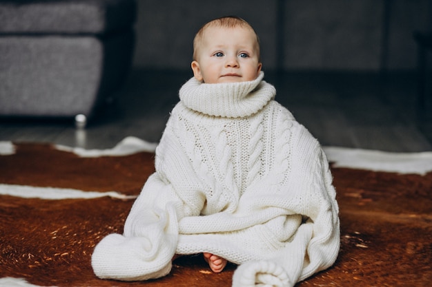 Petit mignon petit garçon assis sur le sol en pull chaud