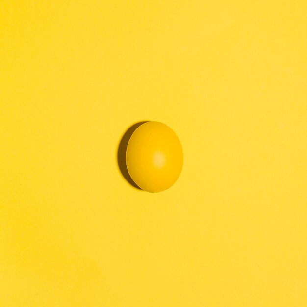 Petit oeuf de Pâques jaune sur une table jaune