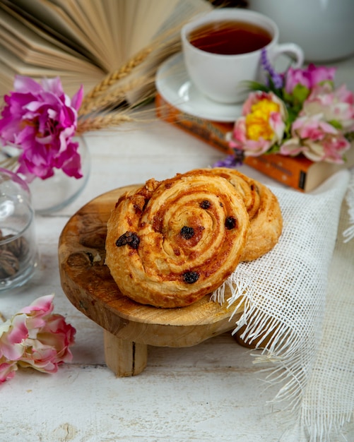 Petit pain aux raisins secs avec une tasse de thé noir