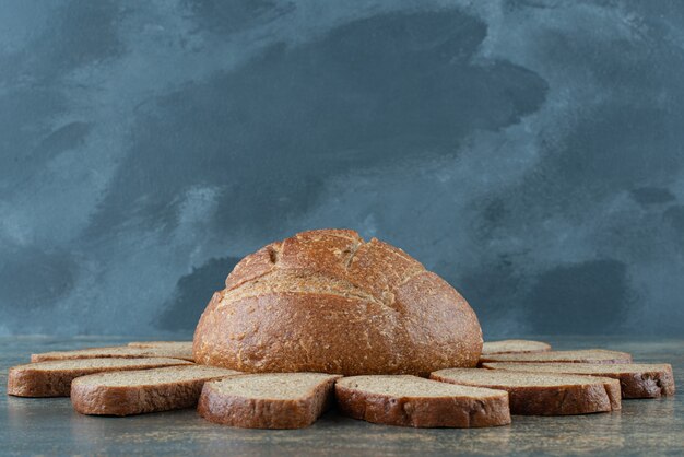 Un petit pain brun frais avec des tranches sur fond de marbre