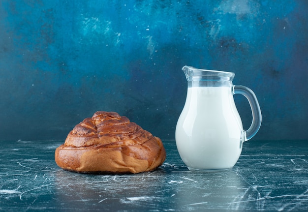 Photo gratuite un petit pain à la cannelle avec un pot de lait de côté. photo de haute qualité