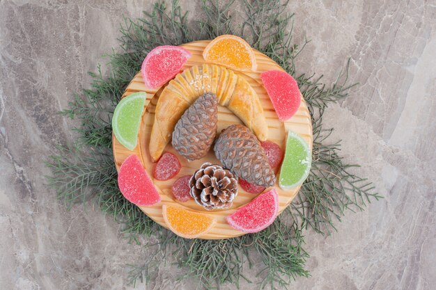 Petit pain croissant sur un plateau à décor de marmelade et pomme de pin sur marbre.