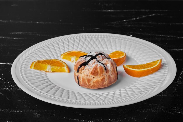 Un petit pain avec du sirop de chocolat et des oranges.