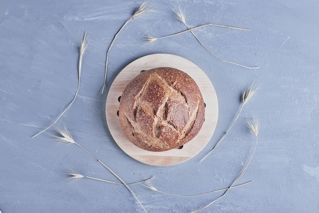 Petit pain rond fait à la main sur un plateau en bois.