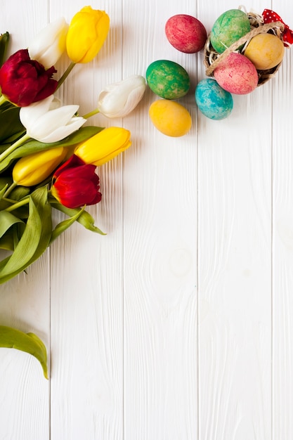 Photo gratuite petit panier avec des oeufs près de tulipes