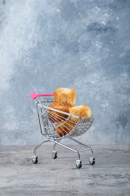 Photo gratuite un petit panier rose de délicieux biscuits placés sur une table en marbre.