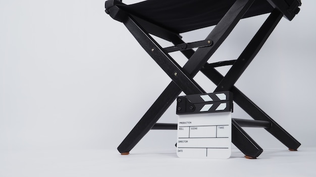 Petit panneau de clapet ou ardoise de cinéma avec chaise de réalisateur noire utilisée dans la production vidéo ou l'industrie du cinéma et du cinéma. c'est mis sur fond blanc.
