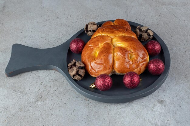 Petit plat de service avec un petit pain sucré sur une table en marbre.