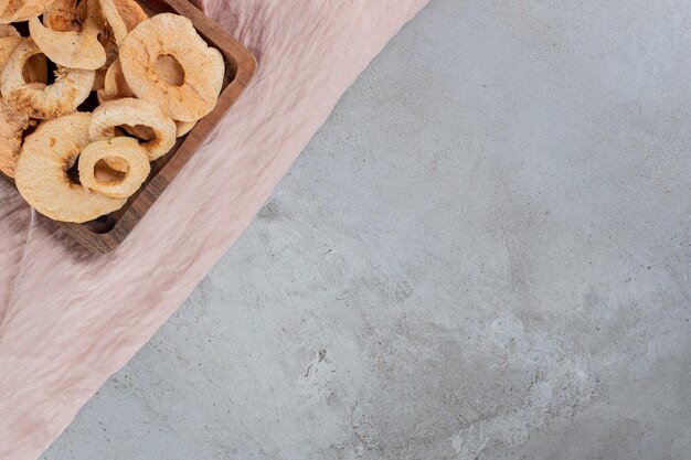 Petit plateau d'anneaux de pommes frites sur table en béton.