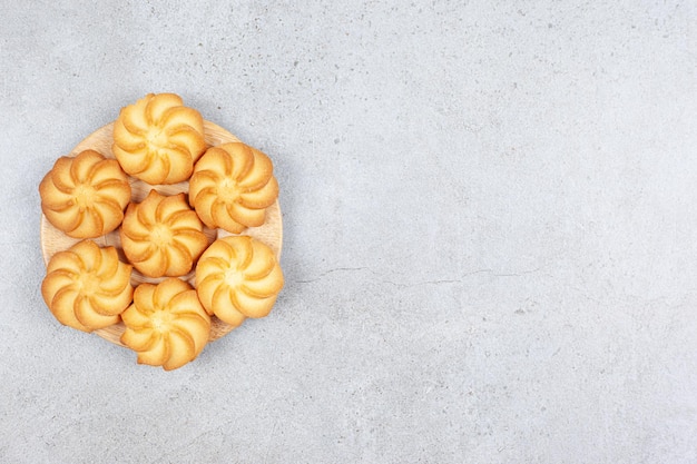 Un petit plateau de biscuits en bois sur fond de marbre.