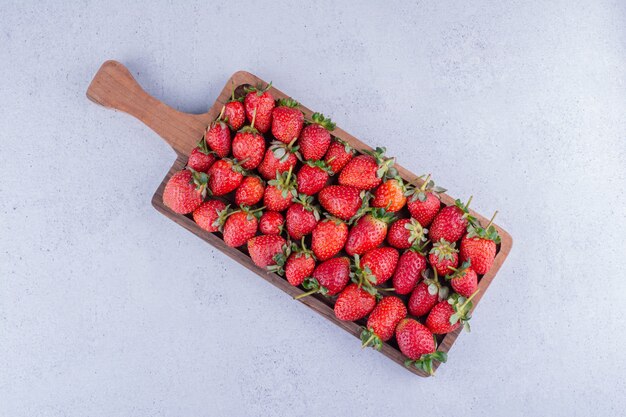 Petit plateau en bois rempli de fraises fraîches sur fond de marbre. photo de haute qualité