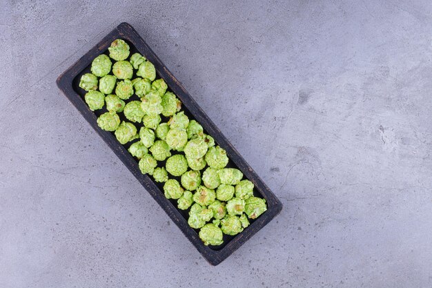 Petit plateau noir rempli d'une poignée de bonbons pop-corn sur fond de marbre. photo de haute qualité