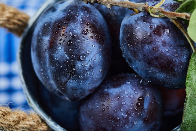 Photo gratuite petit seau de prunes de jardin sur une nappe bleue. photo de haute qualité