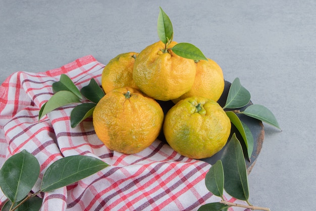 Un petit tas de mandarines sur une serviette sur du marbre.