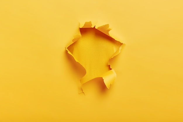 Petit trou de papier avec côtés déchirés sur un espace jaune pour votre texte