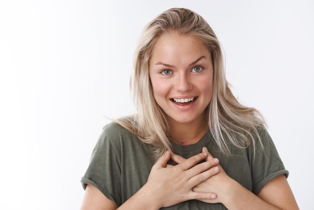 petite amie étonnée suggestion inattendue pressant les paumes contre la poitrine abasourdie et impressionnée souriante haletant d'amusement et d'excitation debout sur blanc