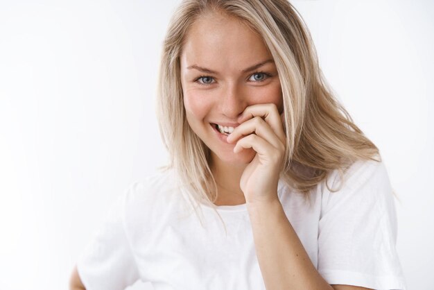 Petite amie gloussant sourire coning flirty avec les doigts regardant la caméra de manière ludique