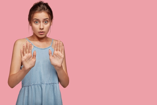 Une petite amie sérieuse et perplexe tire les paumes sans aucun geste, nie avoir rendez-vous avec un inconnu, fait un panneau d'arrêt, a une expression inquiète