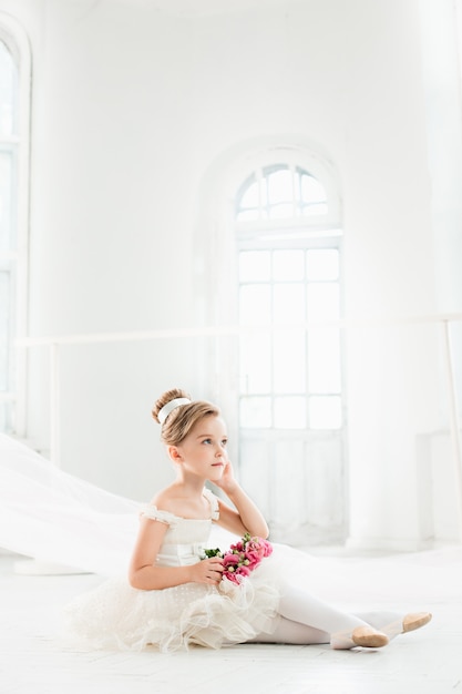 Petite balerine en tutu blanc en classe à l'école de ballet