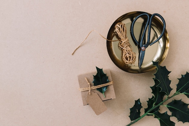 Petite boîte-cadeau avec un dépliant vert noué sur une table marron