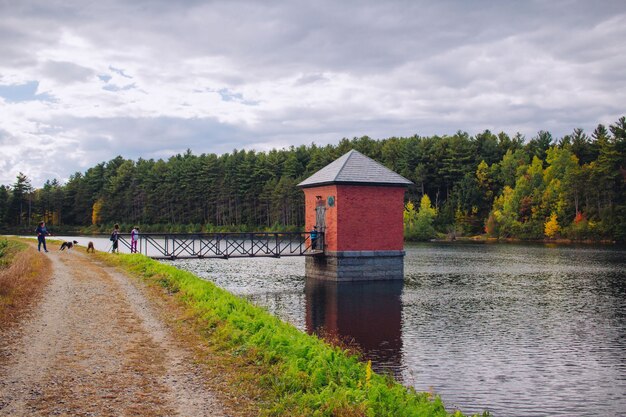 Petite cabane rouge construite sur une rivière et reliée à un pont avec un paysage naturel incroyable