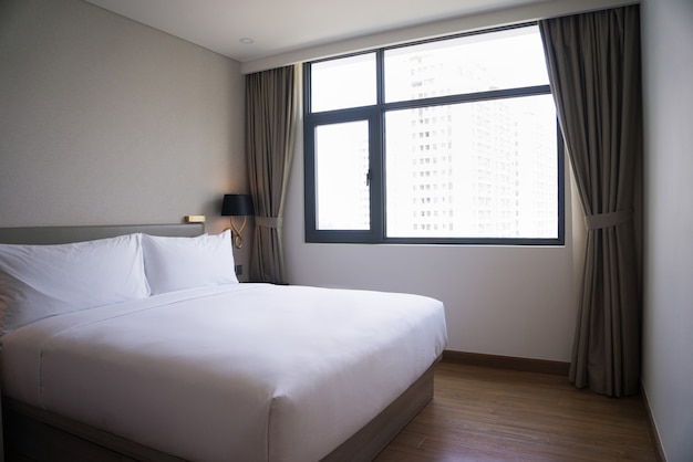 Petite chambre à coucher avec lit double, linge blanc et fenêtre.