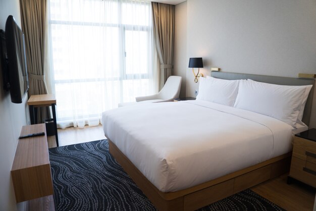 Petite chambre d&#39;hôtel avec des murs blancs et une fenêtre panoramique.