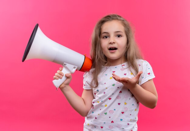 Petite écolière portant un t-shirt blanc tenant haut-parleur sur mur rose isolé