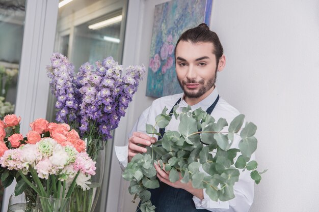 Photo gratuite petite entreprise. fleuriste mâle en magasin de fleurs.