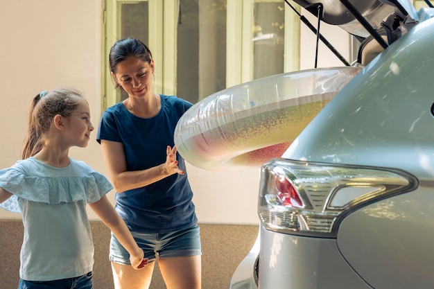 Petite famille voyageant en vacances avec gonflable et bagages dans le coffre de l'automobile. Mère avec jeune enfant partant en vacances d'été au bord de la mer. Partir à l'aventure avec un véhicule.