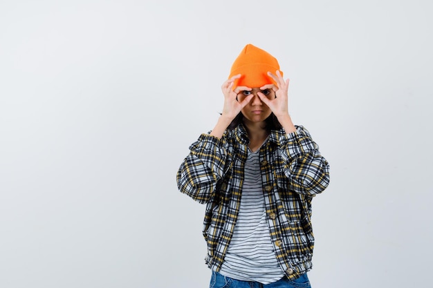 Petite femme en bonnet veste t-shirt montrant un geste de lunettes à la mignonne