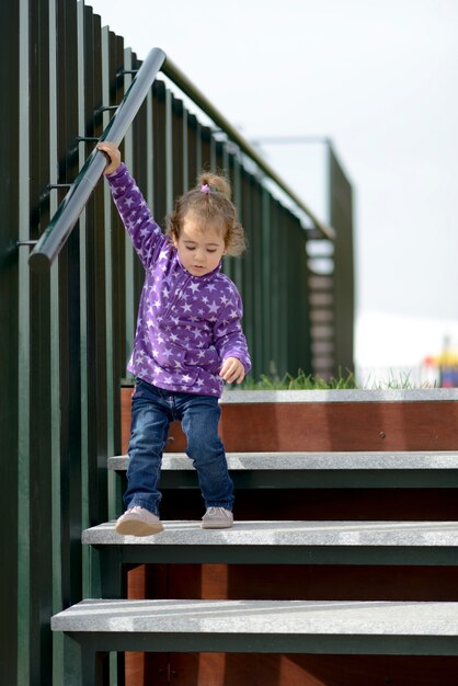 Petite fille de 20 mois descendant des escaliers en plein air