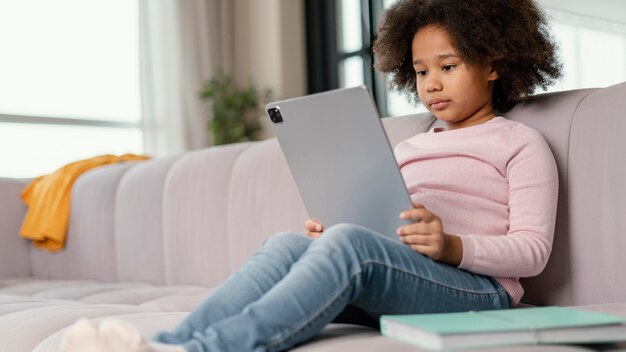 Petite fille à l'aide de tablette à la maison