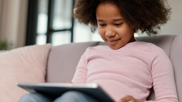 Petite fille à l'aide de tablette à la maison