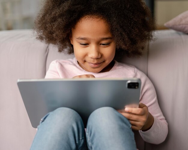 Petite fille à l'aide de tablette à la maison