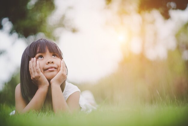 Petite fille allongée confortablement sur l&#39;herbe et souriant