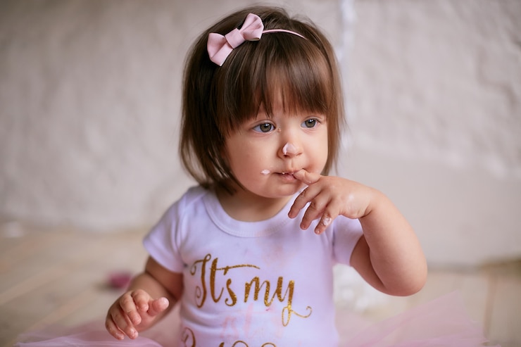 Photo gratuit petite fille d'anniversaire. charmant bébé en robe rose est assis sur la chaise