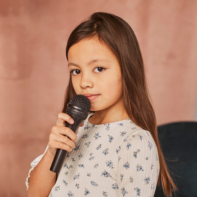 Petite fille apprenant à chanter à la maison avec microphone