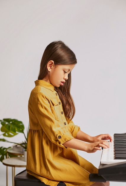 Petite fille apprenant à jouer au clavier électronique à la maison