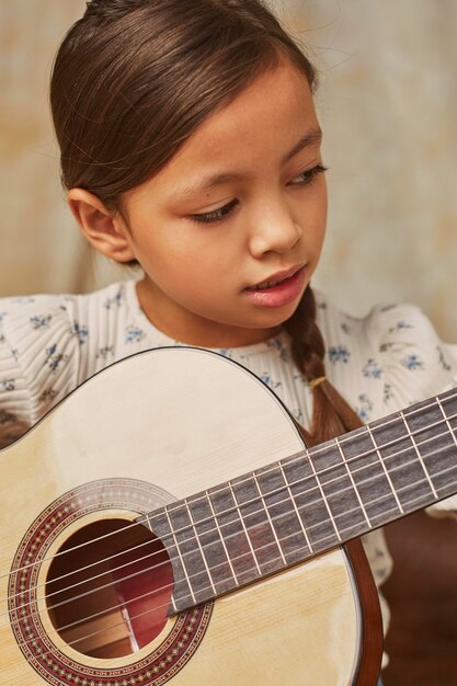 Petite fille apprenant à jouer de la guitare à la maison